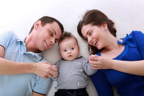Family laying down on carpet with young baby